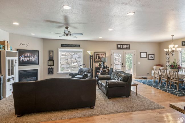 Living room featuring a chandelier, wood finished floors, a ceiling fan, a textured ceiling, and french doors | Image 7