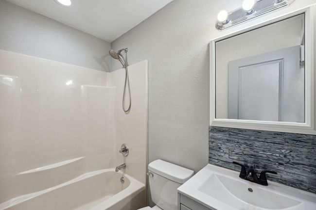 Full bathroom with a textured wall, tasteful backsplash, shower / tub combination, and vanity | Image 15