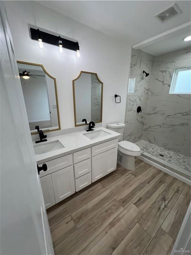 Bathroom 1 with toilet, visible vents, a sink, and a walk in shower | Image 7