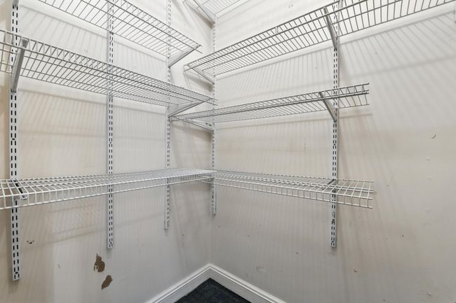 Generously sized walk-in closet with wall-mounted wire shelving for organized storage. | Image 25