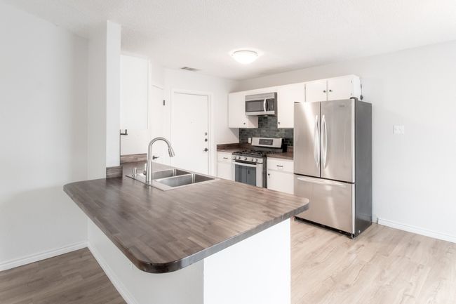 Kitchen featuring appliances with stainless steel finishes, dark countertops, a peninsula, and light wood-style floors | Image 11