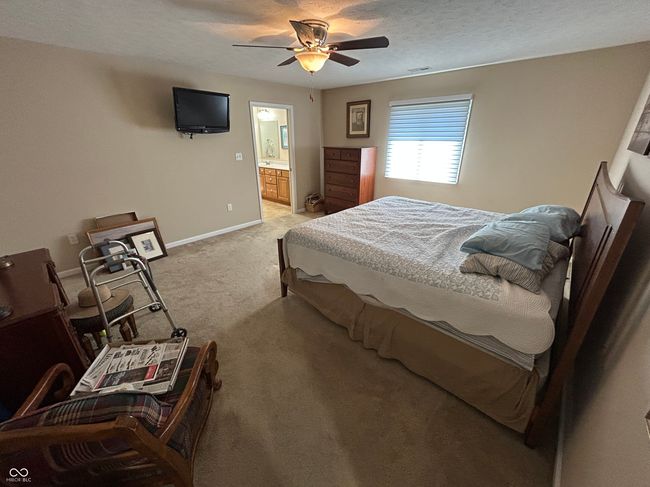 bedroom with light carpet, baseboards, visible vents, ceiling fan, and ensuite bath | Image 12