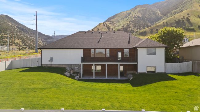Rear view of property with a patio area, a mountain view, and a shingled roof | Image 46