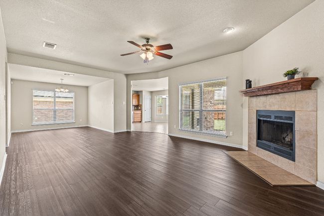 Unfurnished living room with a fireplace, dark wood-style flooring, a textured ceiling, a ceiling fan, and a chandelier | Image 15