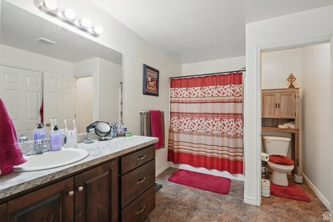 Full bathroom with visible vents, baseboards, toilet, vanity, and stone finish flooring | Image 24