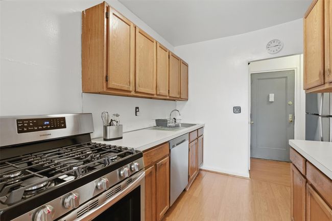 Kitchen with stainless steel appliances, light countertops. | Image 5