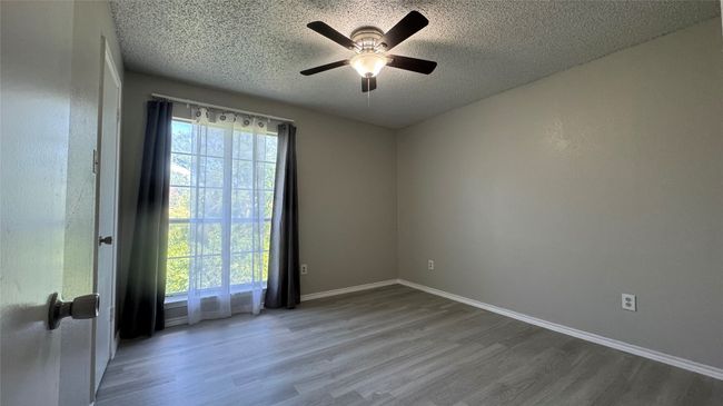 Spare room featuring wood finished floors, a textured ceiling, a ceiling fan, and baseboards | Image 15