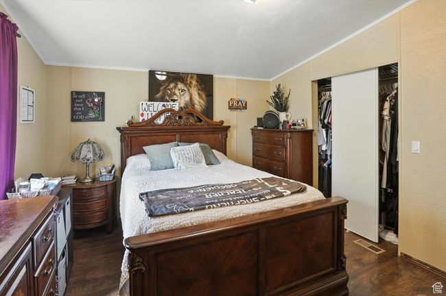 Bedroom featuring dark wood-style flooring, crown molding, and a closet | Image 12