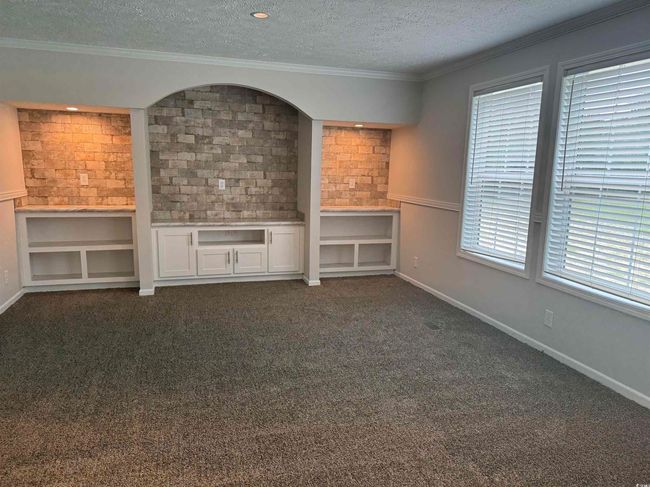 Unfurnished living room with a textured ceiling, ornamental molding, and dark colored carpet | Image 33