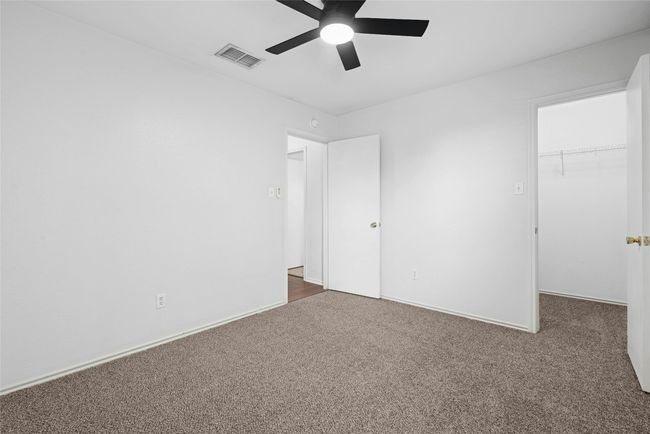 Unfurnished bedroom featuring carpet, a spacious closet, a closet, and a ceiling fan | Image 24