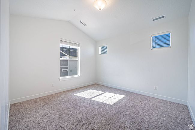 Unfurnished room featuring a healthy amount of sunlight, lofted ceiling, visible vents, and carpet | Image 8