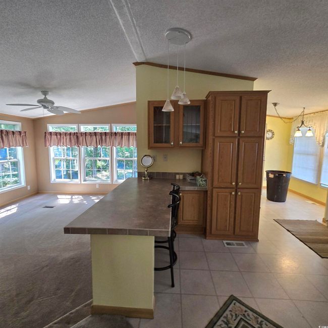 Kitchen with a peninsula, lofted ceiling, healthy amount of natural light, a textured ceiling, and brown cabinets | Image 18