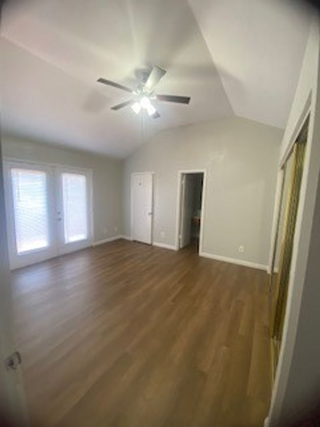 Unfurnished bedroom featuring lofted ceiling, dark wood-style floors, baseboards, and ceiling fan | Image 17