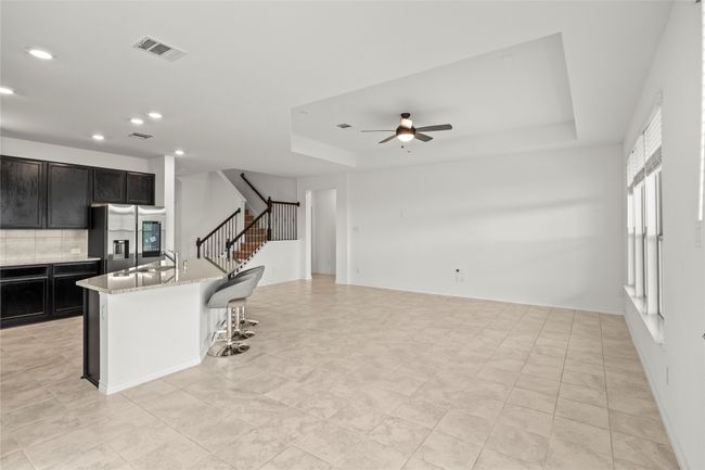 Kitchen with stainless steel fridge, a ceiling fan, recessed lighting, a raised ceiling, and tasteful backsplash | Image 5