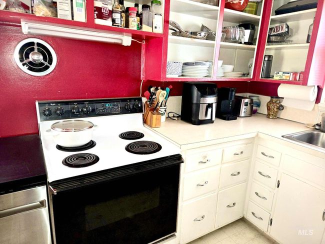 Kitchen featuring electric range oven, white cabinets, light countertops, and light tile patterned flooring | Image 16