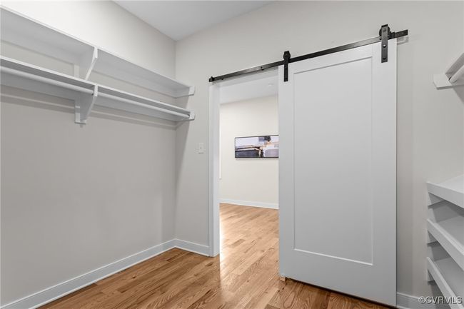 Walk in closet with a barn door and light wood finished floors | Image 37