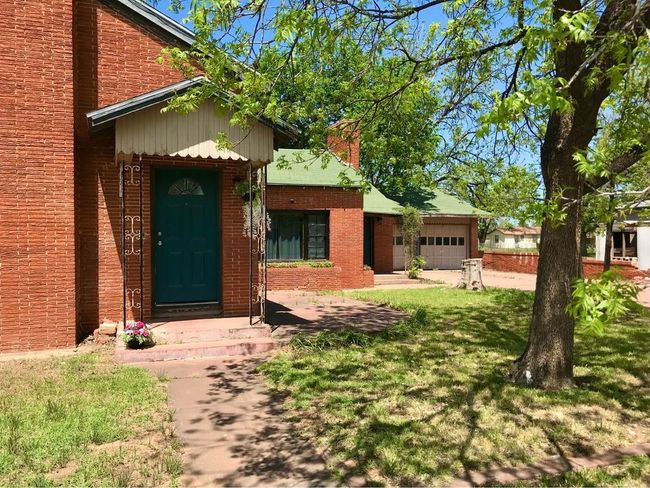 View of front facade featuring an attached garage, a chimney, a front yard, and brick siding | Image 20