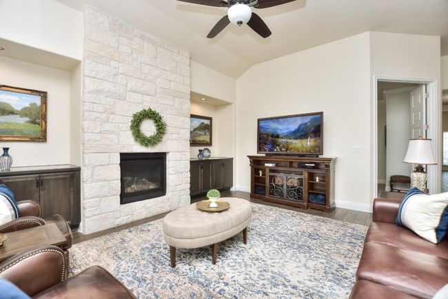 Living room with lofted ceiling, a ceiling fan, wood finished floors, a fireplace, and baseboards | Image 13