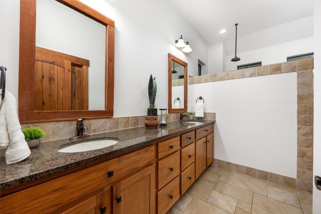 The primary bath boasts a luxurious double vanity with granite countertops and rich wood cabinetry, offering ample storage. The oversized walk-in shower features a tiled surround and rainfall shower head, creating a spa-like atmosphere. | Image 14