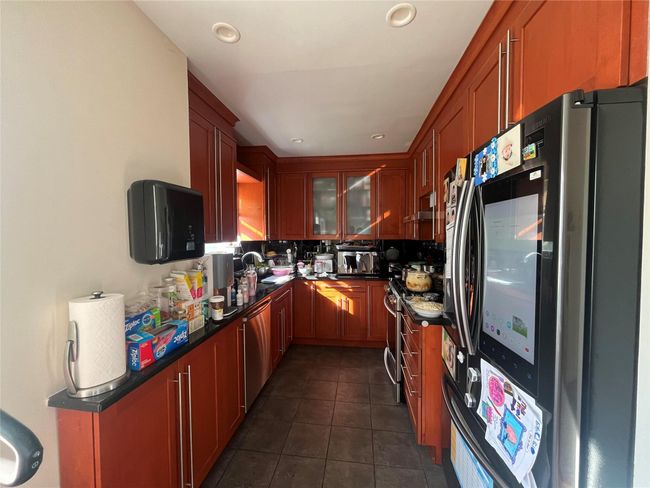 Kitchen with dark countertops, stainless steel appliances, dark tile patterned flooring, and a sink | Image 4