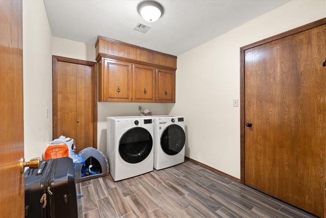 Washroom featuring independent washer and dryer, cabinet space, wood tiled floors, and baseboards | Image 33