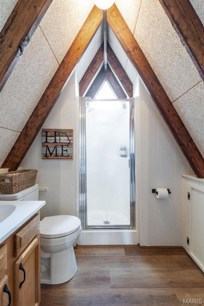 Full bath featuring vanity, wood finished floors, lofted ceiling with beams, a shower stall, and toilet | Image 42