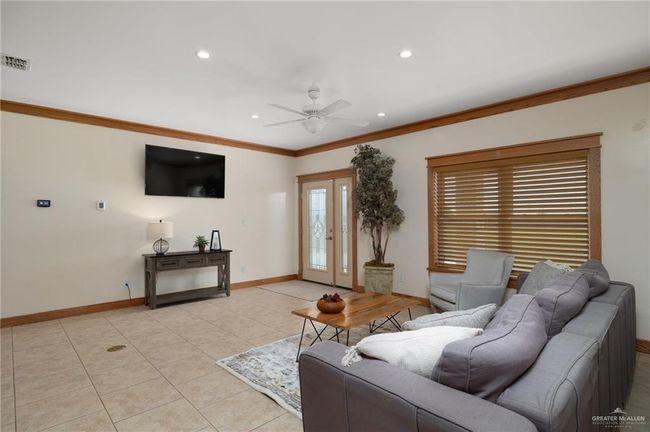 Living room with ceiling fan, french doors, light tile patterned floors, and ornamental molding | Image 7