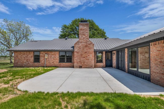 Back of house with a patio, a chimney, metal roof, and brick siding | Image 7