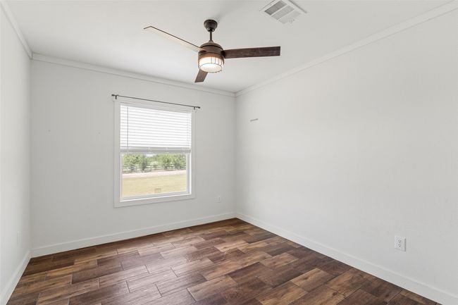 Unfurnished room featuring dark wood-type flooring, ceiling fan, and crown molding | Image 22