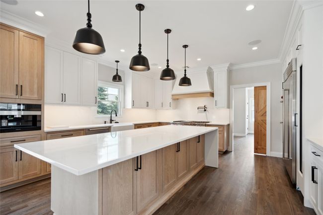 Kitchen featuring custom exhaust hood, light countertops, a kitchen island, dark wood-style floors, and recessed lighting | Image 9