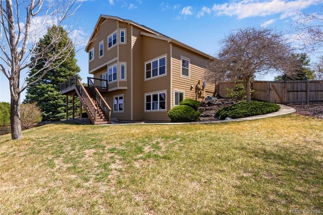 Rear view of house featuring a deck, a yard, fence, and stairs | Image 4