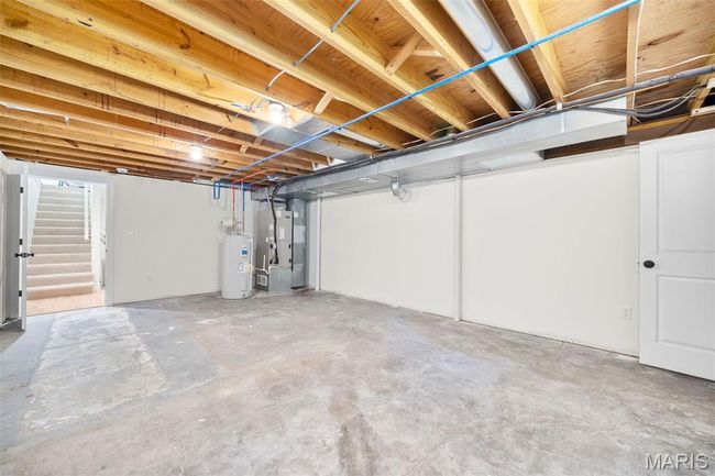 Unfinished basement with electric water heater, stairs, and heating unit | Image 44