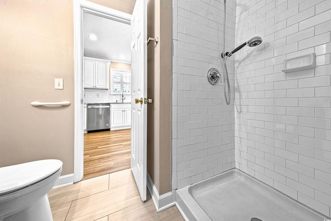 Bathroom featuring wood finished floors, toilet, baseboards, tasteful backsplash, and a stall shower | Image 26