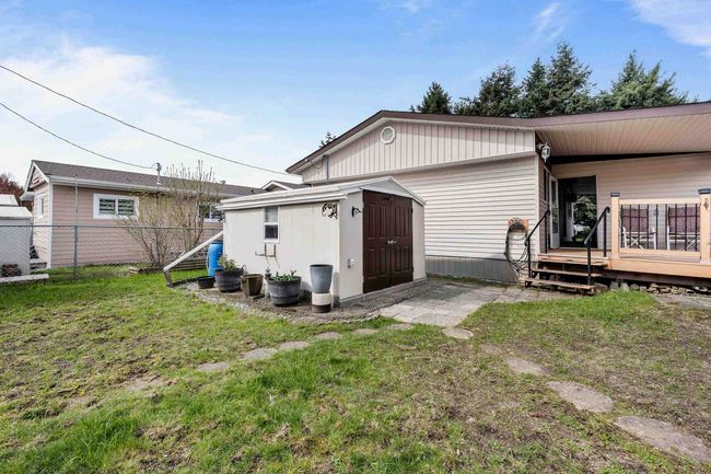 Rear view of house featuring an outbuilding, a shed, fence, and a lawn | Image 25