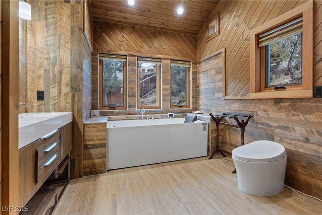 Full bath with a soaking tub, wooden ceiling, wood walls, and toilet | Image 62