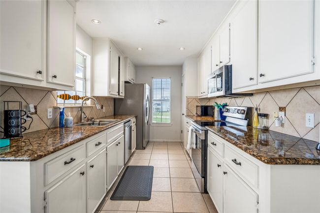 Galley kitchen featuring granite countertops. | Image 8