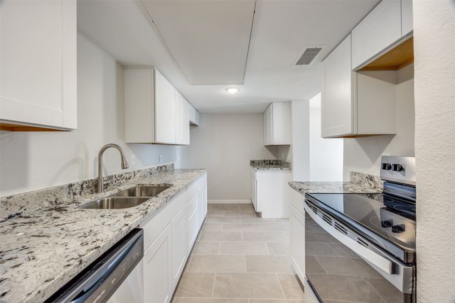 Kitchen with sink, white cabinetry, stainless steel appliances, and light tile patterned floors | Image 13