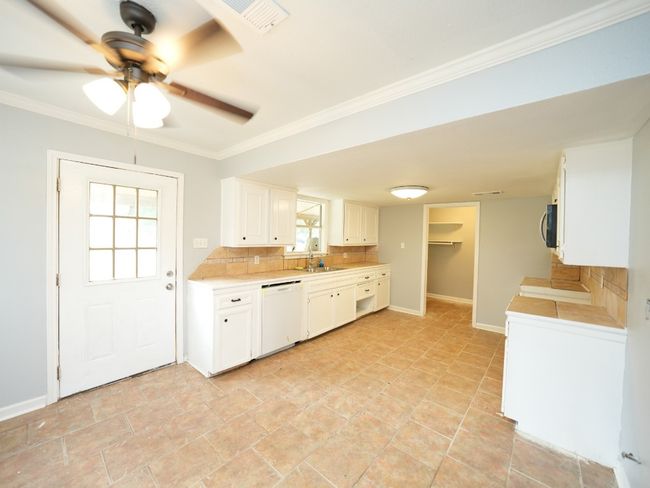 Kitchen featuring dishwasher, light countertops, ornamental molding, white cabinets, and ceiling fan | Image 11