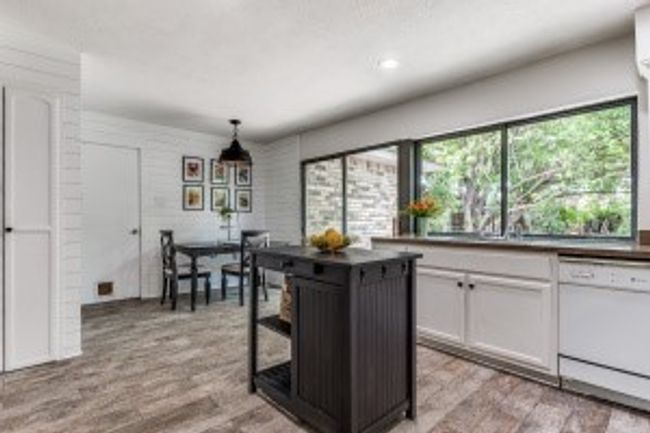 Kitchen featuring dishwasher, white cabinetry, hanging light fixtures, and light wood-type flooring | Image 13
