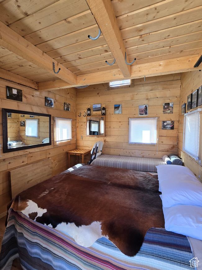 Bedroom featuring beamed ceiling, wooden walls, and wood ceiling | Image 123