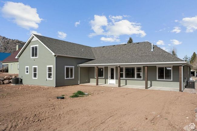 Rear view of property featuring a patio area, roof with shingles, central AC, and driveway | Image 47