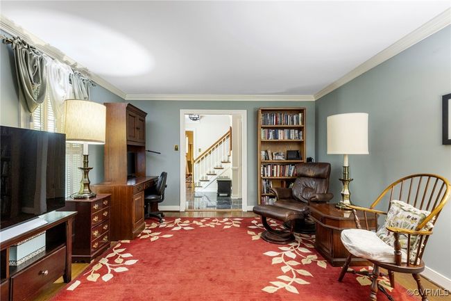 Living area featuring crown molding, wood finished floors, an office area, and stairs | Image 5