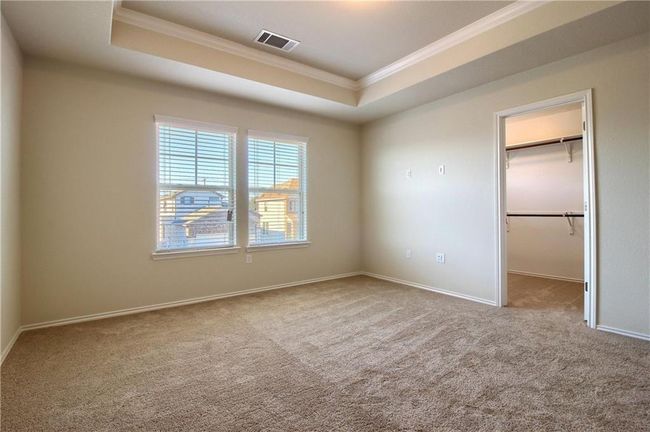 Unfurnished bedroom with crown molding, carpet flooring, a tray ceiling, a spacious closet, and baseboards | Image 23