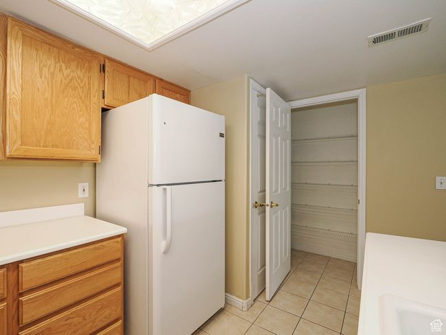 Kitchen featuring light countertops, visible vents, a sink, light tile patterned floors, and freestanding refrigerator | Image 12