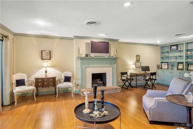 Living room with a fireplace, visible vents, crown molding, and wood finished floors | Image 13