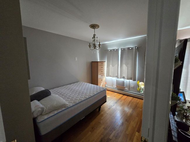 Bedroom with a baseboard radiator, a chandelier, and hardwood / wood-style floors | Image 13