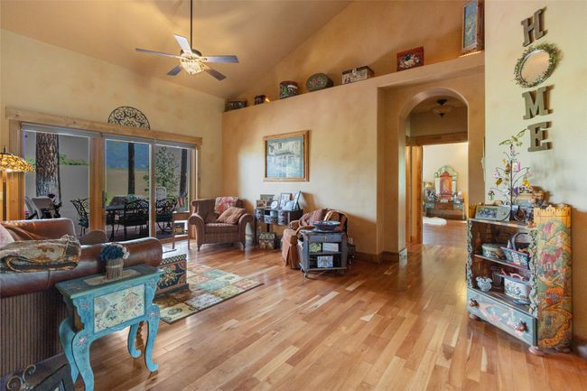 Living area featuring ceiling fan, arched walkways, high vaulted ceiling, and wood finished floors | Image 28