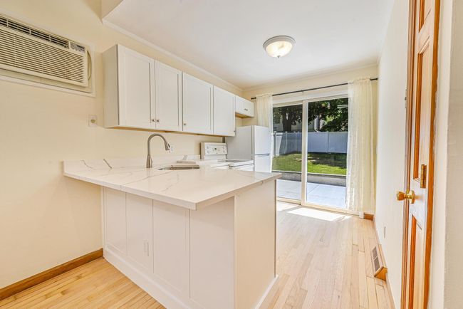 Kitchen with light wood-style floors, white appliances, a peninsula, light stone counters, and ornamental molding | Image 8