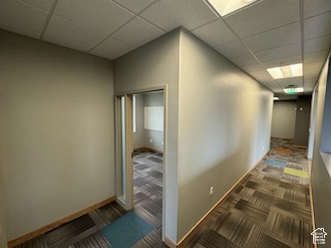 Hallway with a paneled ceiling and carpet floors | Image 37