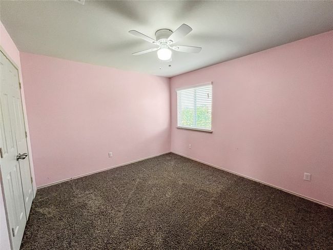 Unfurnished room with ceiling fan and dark colored carpet | Image 17